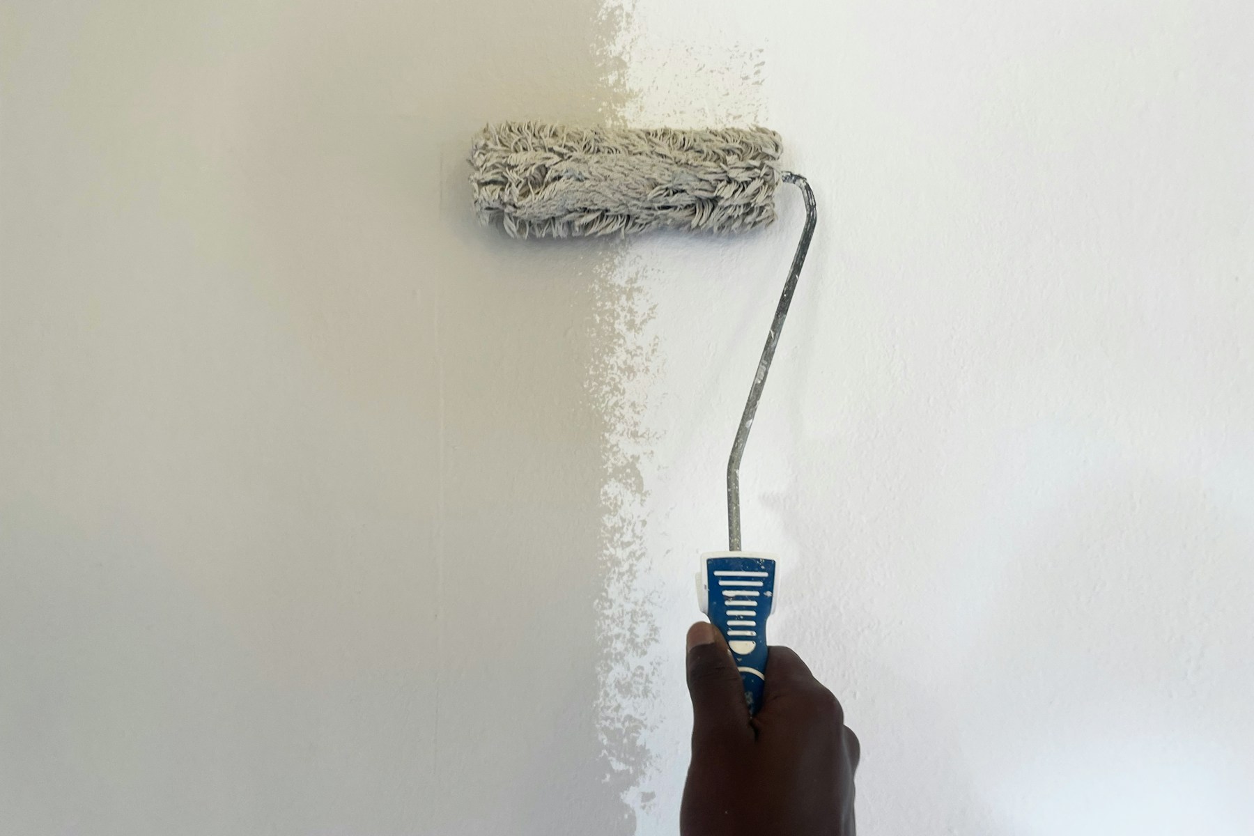 Paint roller applying a coat to a wall